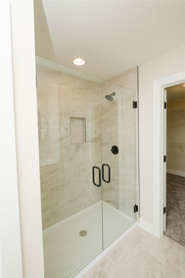 full bath featuring a stall shower, a spacious closet, baseboards, and recessed lighting