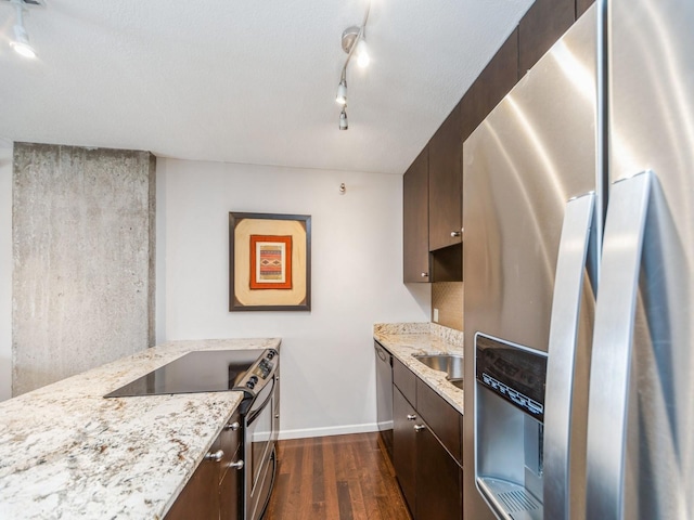 kitchen featuring appliances with stainless steel finishes, dark wood-style flooring, dark brown cabinets, and light stone countertops