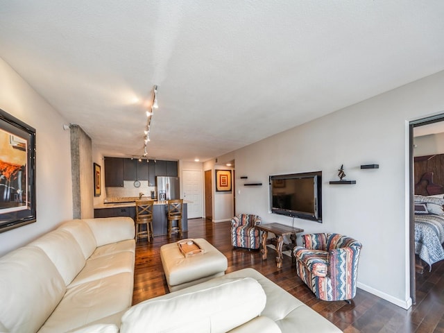 living room featuring track lighting, dark wood finished floors, and baseboards