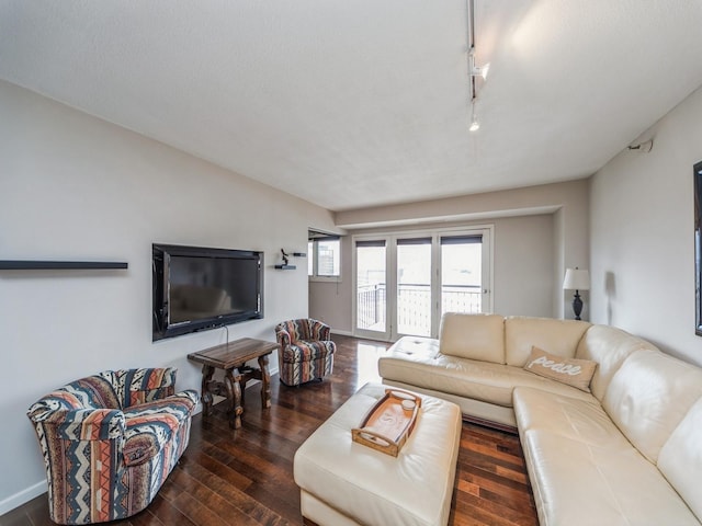 living area with rail lighting, dark wood finished floors, and baseboards