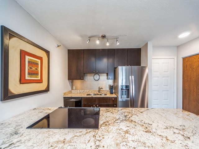 kitchen with light stone countertops, black appliances, tasteful backsplash, and a sink