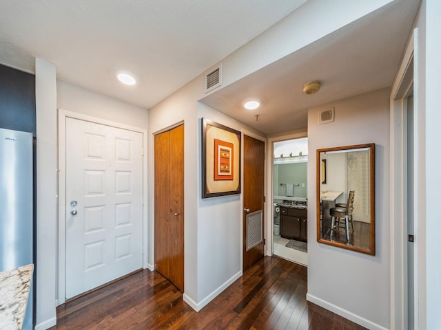 foyer with dark wood-style flooring, visible vents, and baseboards