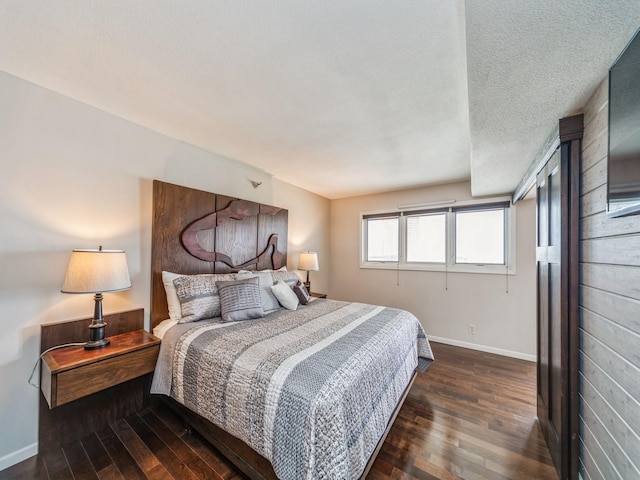 bedroom featuring dark wood finished floors, a textured ceiling, and baseboards