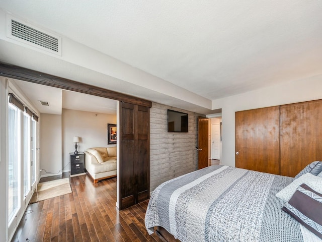 bedroom with dark wood-style floors, a closet, visible vents, and baseboards