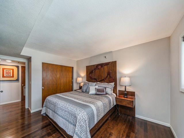 bedroom with a closet, dark wood finished floors, and baseboards