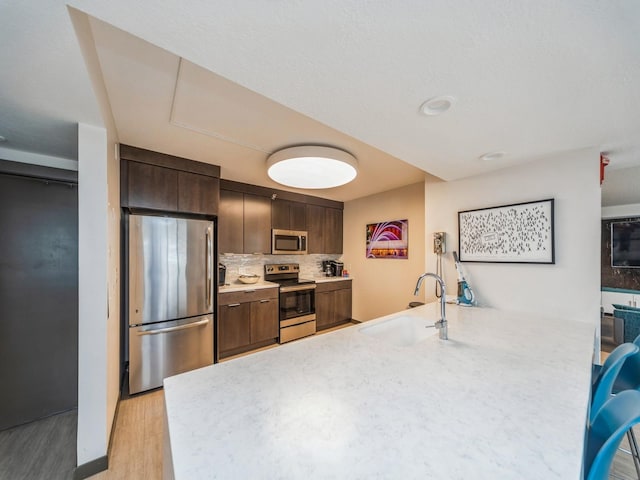 kitchen featuring appliances with stainless steel finishes, light countertops, a sink, and a peninsula