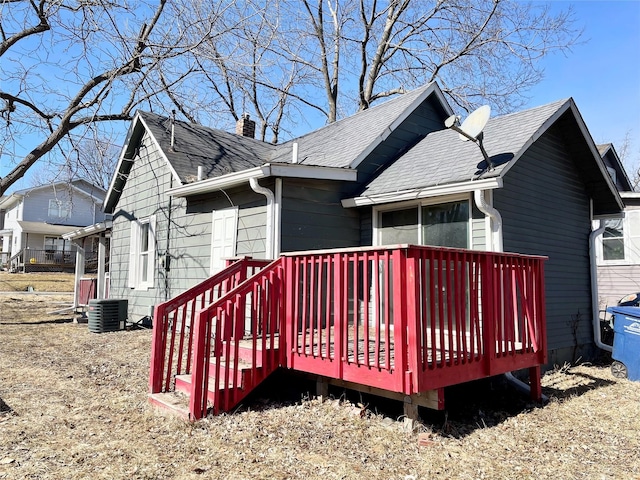 rear view of house with cooling unit, roof with shingles, a chimney, and a wooden deck