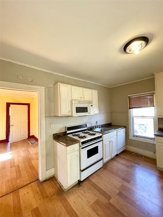 kitchen featuring light wood-style floors, dark countertops, white appliances, and white cabinets