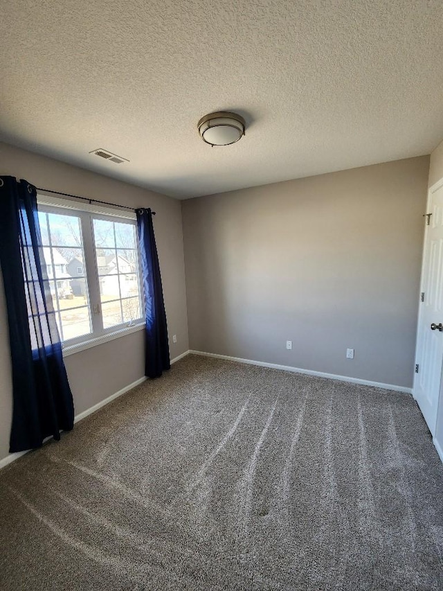 unfurnished room with carpet floors, visible vents, a textured ceiling, and baseboards