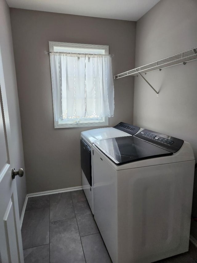 washroom featuring laundry area, dark tile patterned flooring, washer and clothes dryer, and baseboards