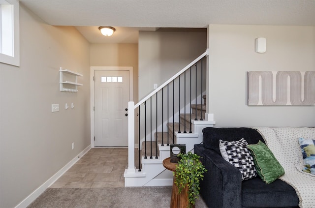 foyer entrance with stairway and baseboards