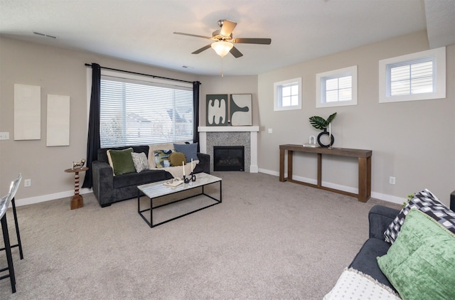 living room with a fireplace, light colored carpet, visible vents, ceiling fan, and baseboards