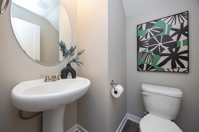 bathroom with baseboards, visible vents, toilet, and wood finished floors