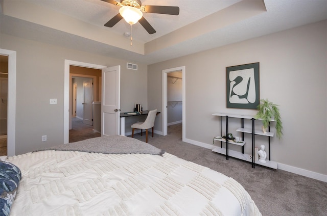 bedroom featuring visible vents, a spacious closet, a tray ceiling, carpet floors, and a closet