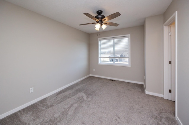 empty room featuring a ceiling fan, light colored carpet, visible vents, and baseboards