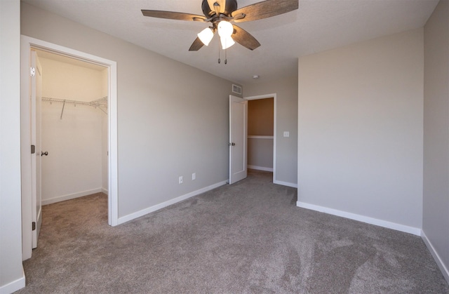 unfurnished bedroom with ceiling fan, carpet flooring, visible vents, baseboards, and a spacious closet