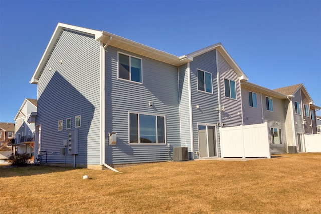 back of house with fence, central AC unit, and a yard