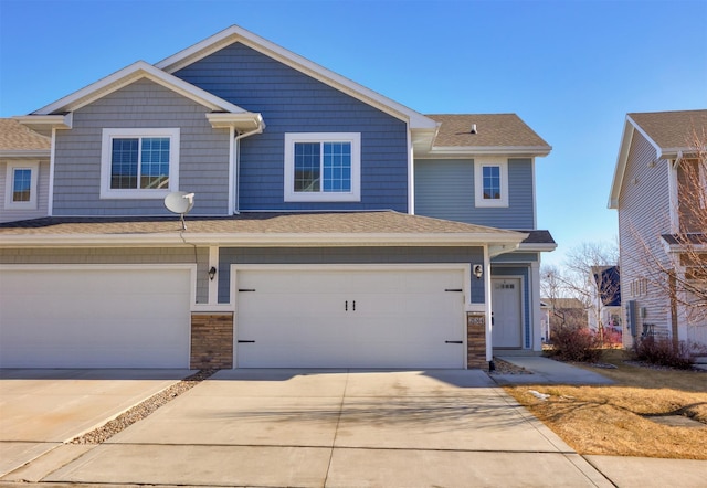 townhome / multi-family property with stone siding, concrete driveway, and a garage