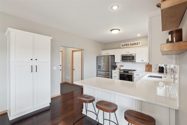 kitchen with stainless steel appliances, light countertops, a sink, and a peninsula