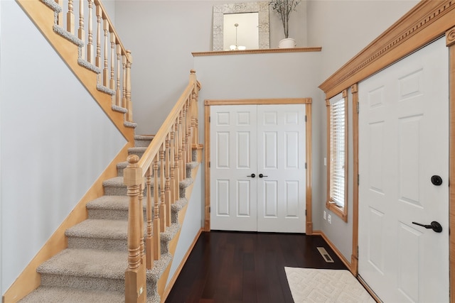 entrance foyer featuring a chandelier, visible vents, a towering ceiling, baseboards, and dark wood-style floors