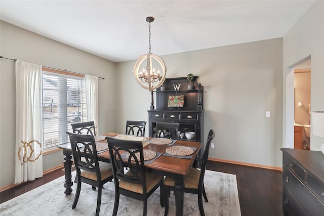 dining area featuring dark wood-type flooring, a notable chandelier, and baseboards