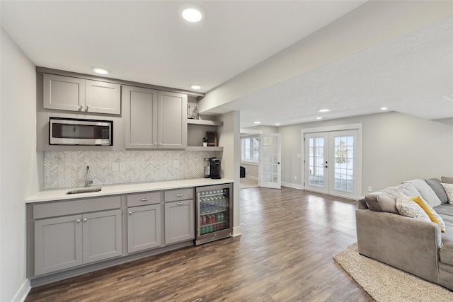 kitchen featuring stainless steel microwave, open floor plan, gray cabinets, light countertops, and a sink