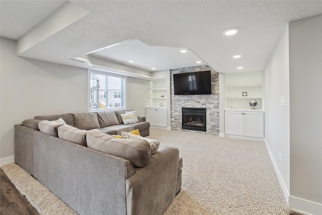 living room featuring a textured ceiling, a stone fireplace, built in features, and baseboards