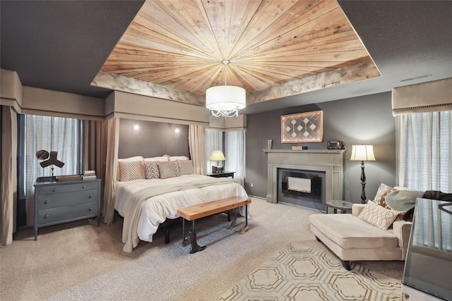 carpeted bedroom with wooden ceiling, a fireplace, a chandelier, and a raised ceiling