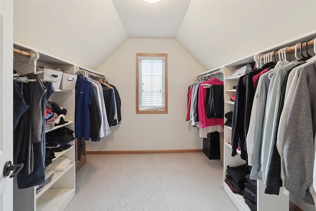 walk in closet with lofted ceiling and light colored carpet