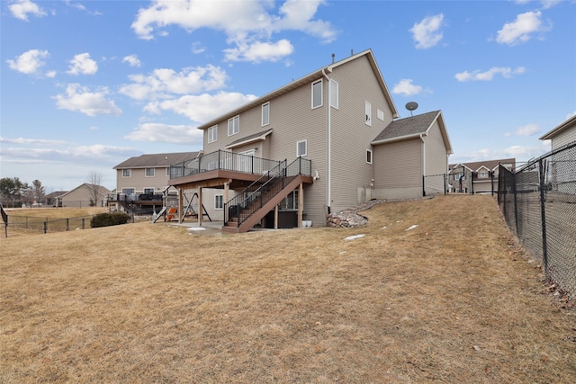 rear view of property featuring a lawn, a fenced backyard, stairway, a gate, and a wooden deck