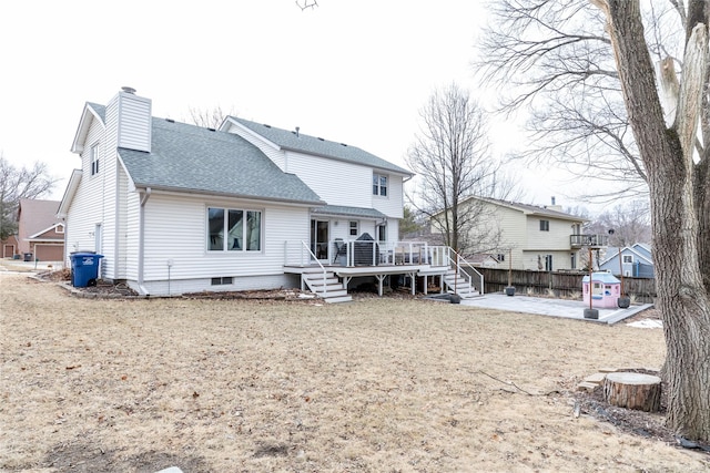 back of property featuring a patio, fence, roof with shingles, a wooden deck, and a chimney