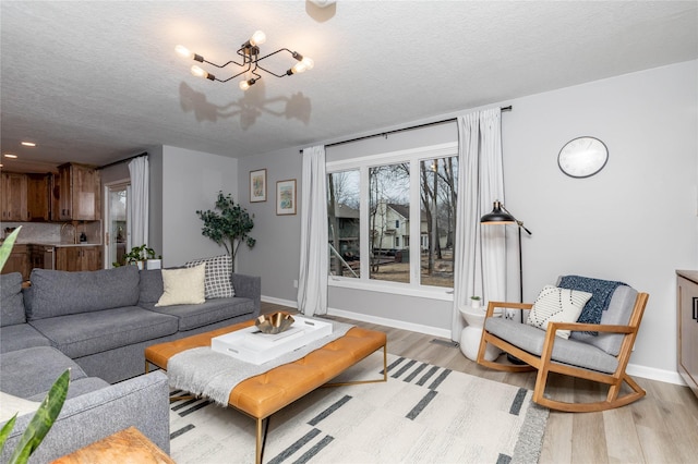 living area with light wood finished floors, baseboards, and a textured ceiling