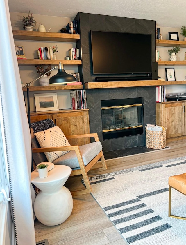 living room with a tiled fireplace and wood finished floors