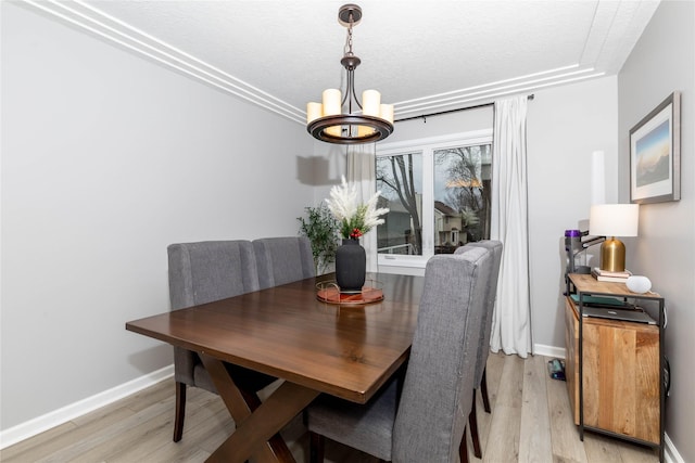 dining room with light wood-type flooring, an inviting chandelier, and baseboards