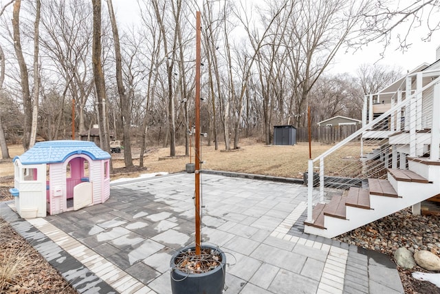 view of patio with a storage shed, fence, stairway, and an outbuilding