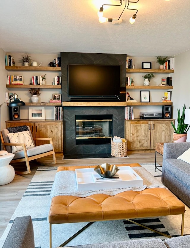 living area with a fireplace, light wood-style flooring, and a textured ceiling