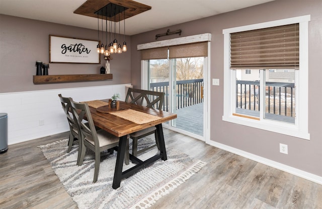 dining room with baseboards, wood finished floors, and wainscoting