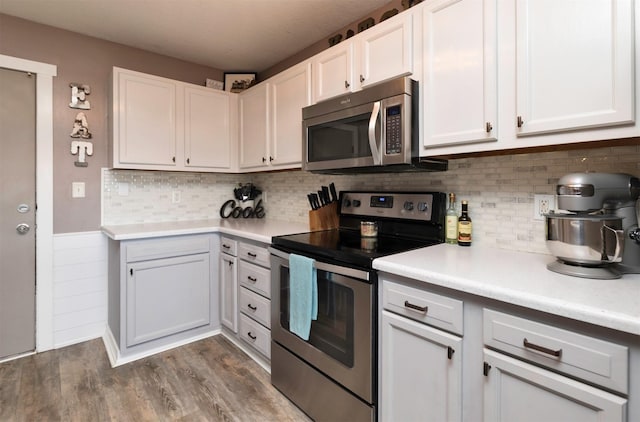 kitchen featuring tasteful backsplash, light countertops, appliances with stainless steel finishes, white cabinets, and wood finished floors