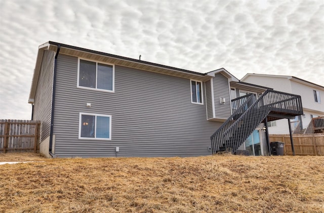 back of house featuring fence, a deck, and stairs