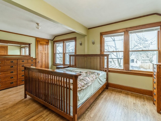 bedroom with light wood-style floors, ornamental molding, and baseboards