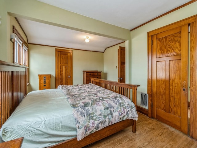 bedroom featuring light wood-style floors, visible vents, and ornamental molding