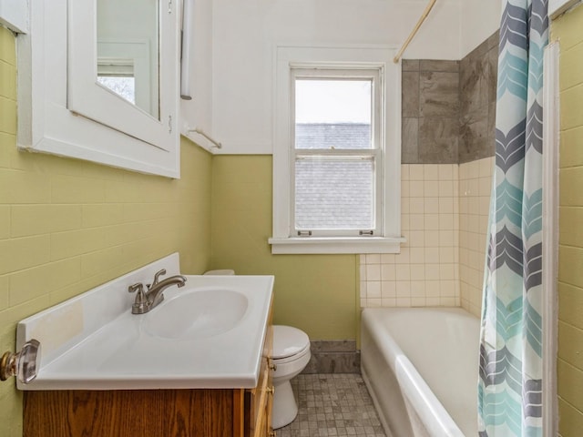 bathroom with toilet, tile walls, vanity, and shower / bathtub combination with curtain