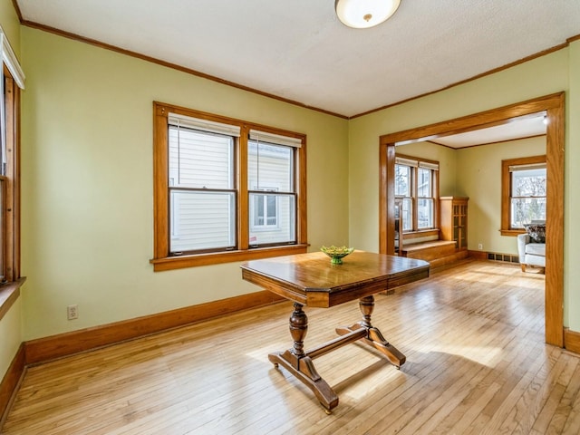 dining room featuring light wood-style flooring, crown molding, visible vents, and baseboards