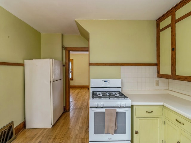 kitchen featuring light countertops, visible vents, decorative backsplash, light wood-style floors, and white appliances