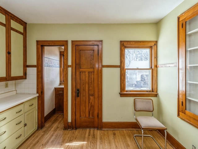 kitchen featuring light wood-style flooring, baseboards, light countertops, and decorative backsplash