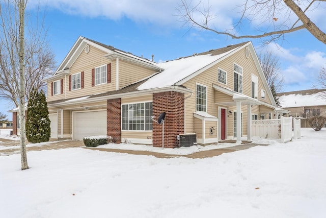 view of front facade with brick siding, fence, an attached garage, and central AC unit