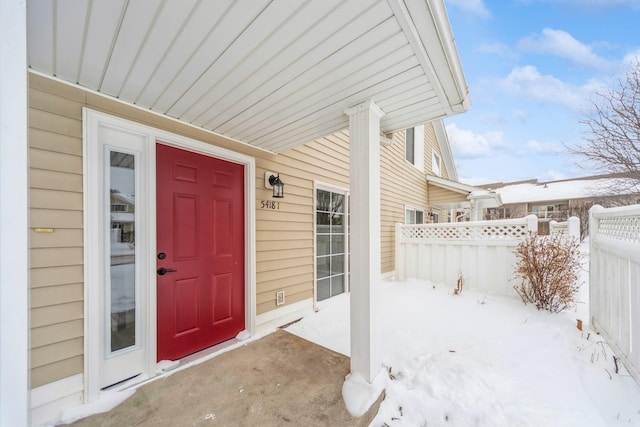 snow covered property entrance with fence