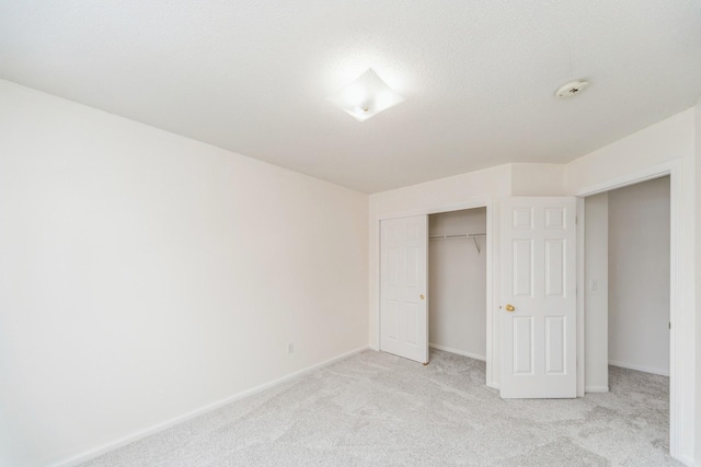 unfurnished bedroom featuring baseboards, a closet, and light colored carpet