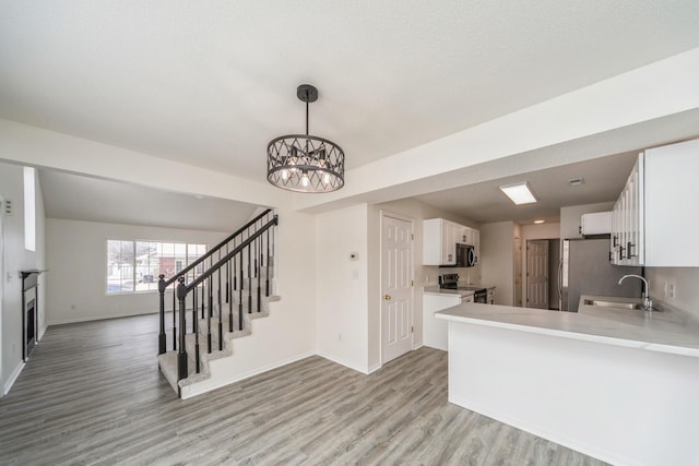 kitchen with light countertops, appliances with stainless steel finishes, open floor plan, white cabinetry, and a peninsula