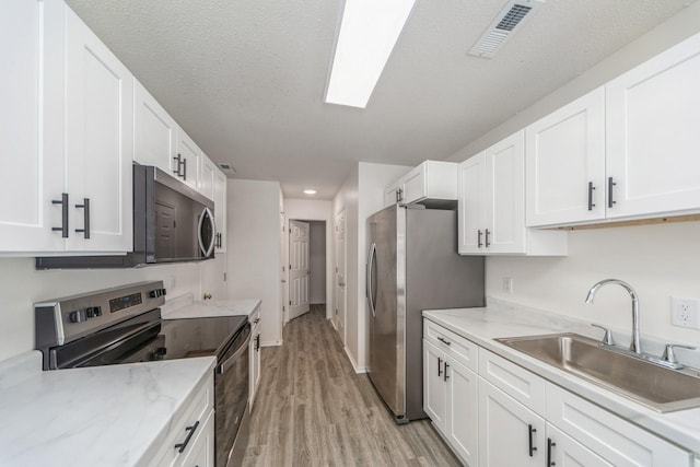 kitchen with white cabinets, visible vents, stainless steel appliances, and a sink